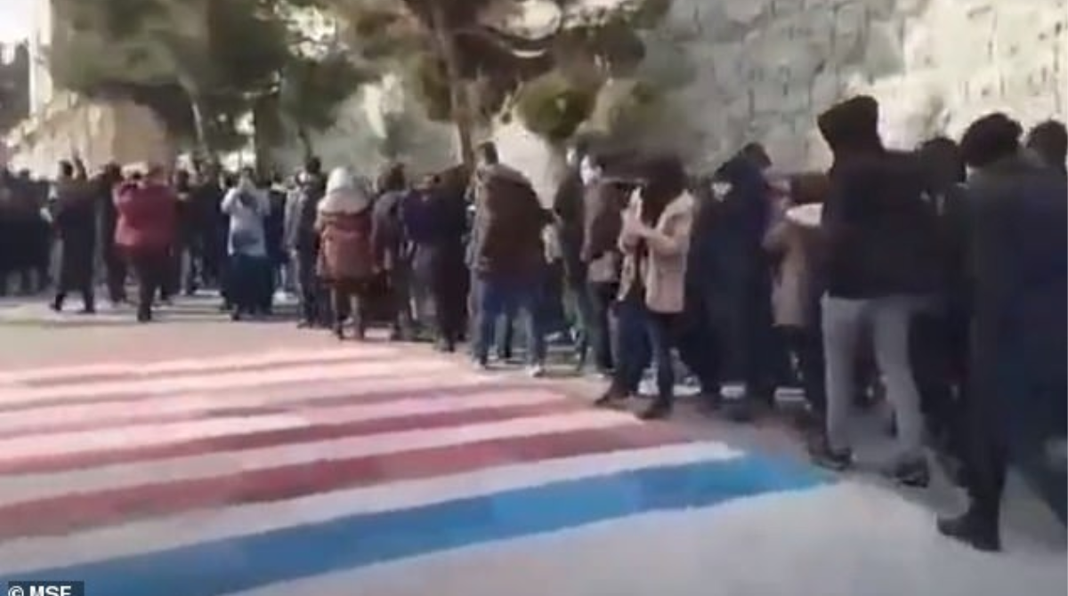 Iranian protesters stepping round US and Israel flags